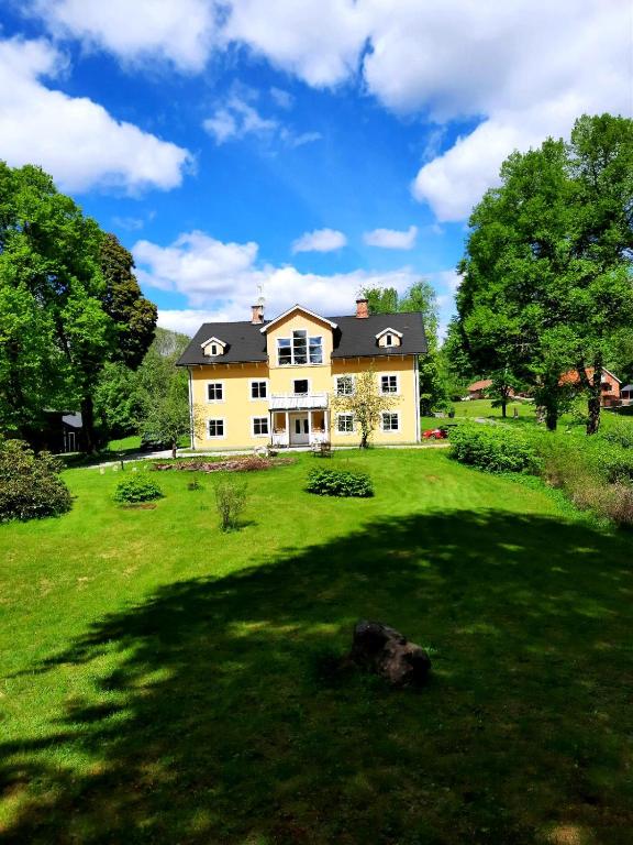 a large house on a green field with trees at Ferienwohnung Käthe in Filipstad