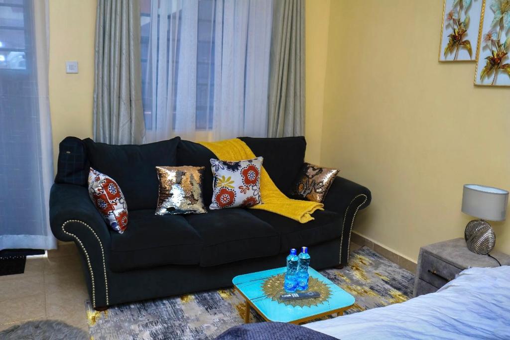 a living room with a black couch with pillows at The Cozy Cranny, Kamakis in Ruiru