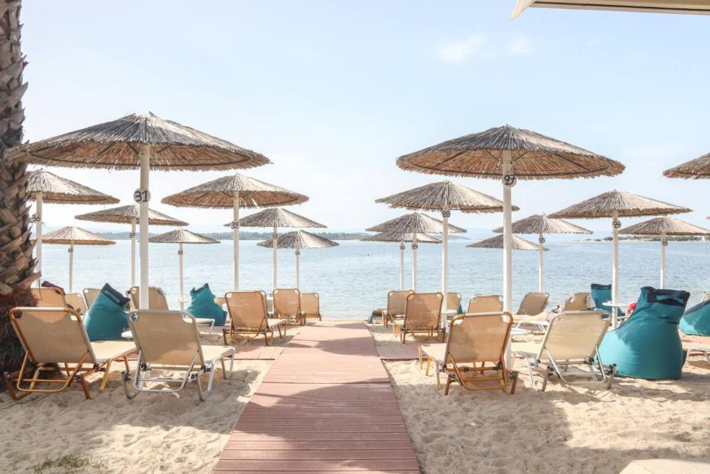 a group of chairs and umbrellas on the beach at Vergos Hotel in Vourvourou