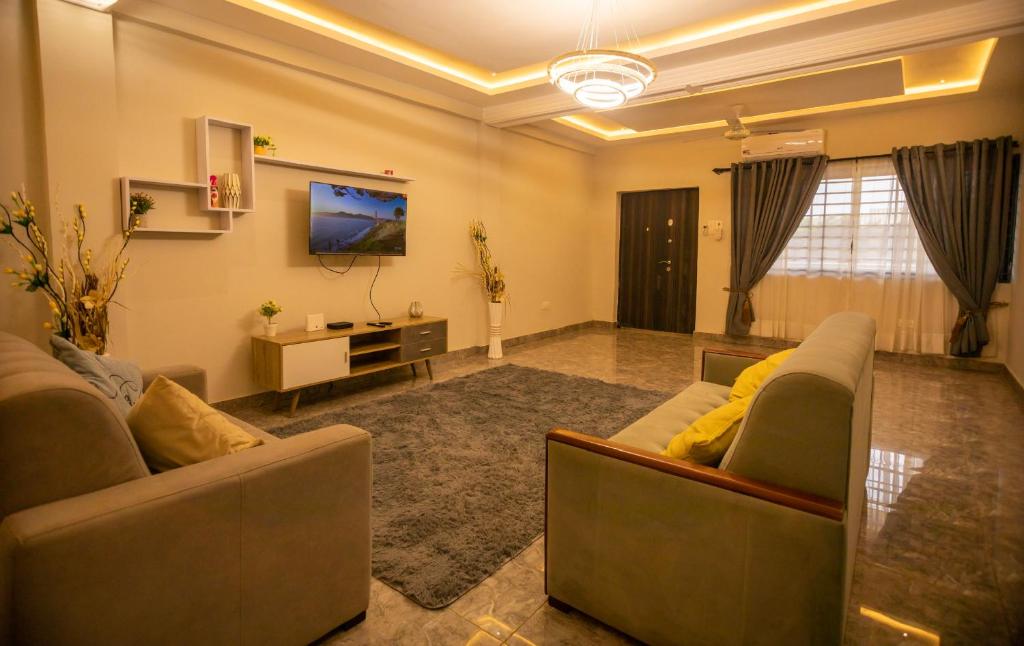 un salon avec deux canapés et une télévision dans l'établissement Agape Villa, à Sékondi