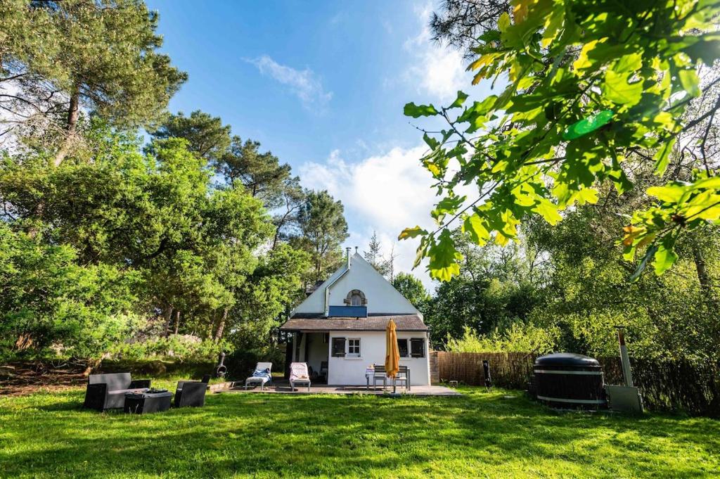 un petit hangar blanc dans une cour avec de l'herbe dans l'établissement Entre Mer et Nature - Bain nordique et sauna, à Clohars-Carnoët