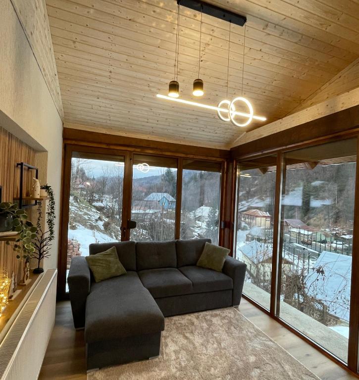 a living room with a couch and large windows at Casa Ceteras in Cavnic
