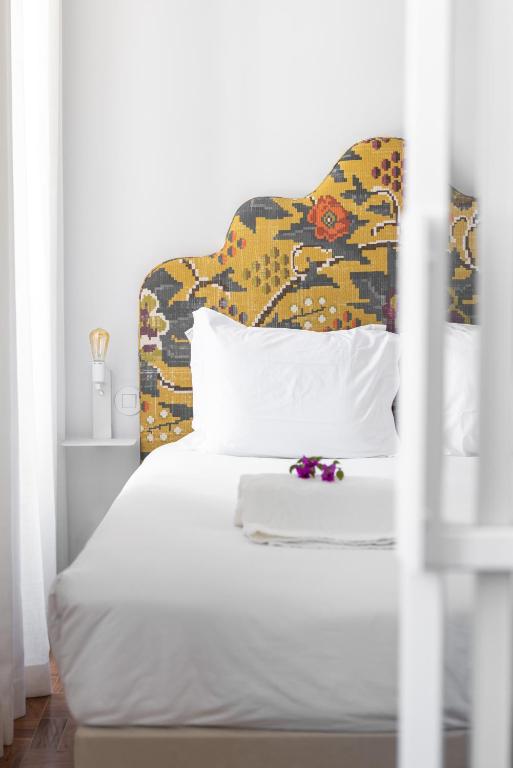 a bed with a headboard and white sheets and pillows at Pergola Boutique Hotel in Cascais