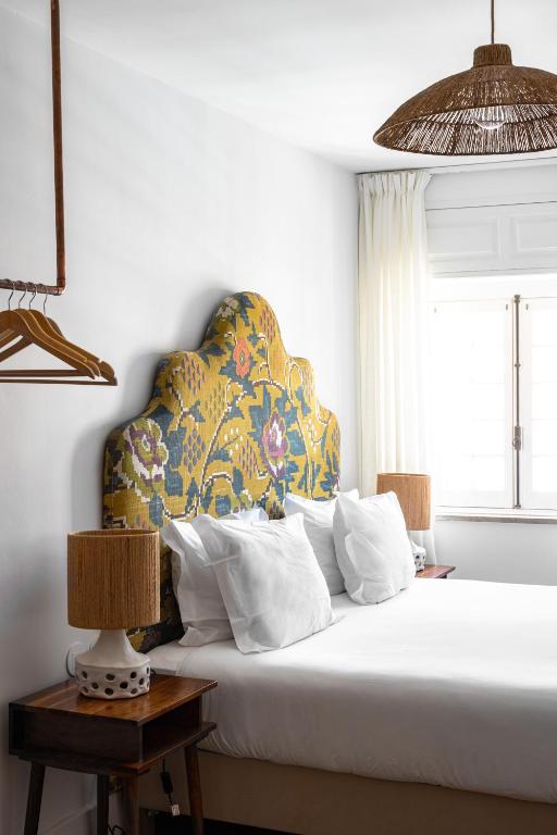 a bedroom with a white bed with a colorful headboard at Pergola Boutique Hotel in Cascais