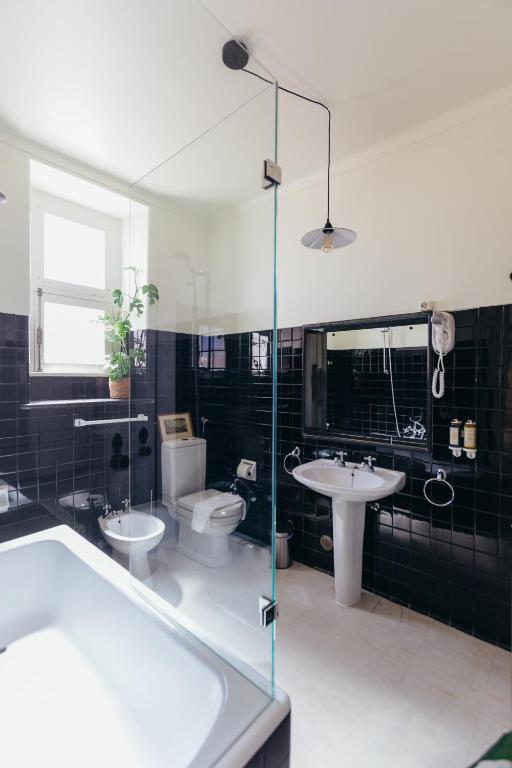 a bathroom with a tub and a toilet and a sink at Pergola Boutique Hotel in Cascais