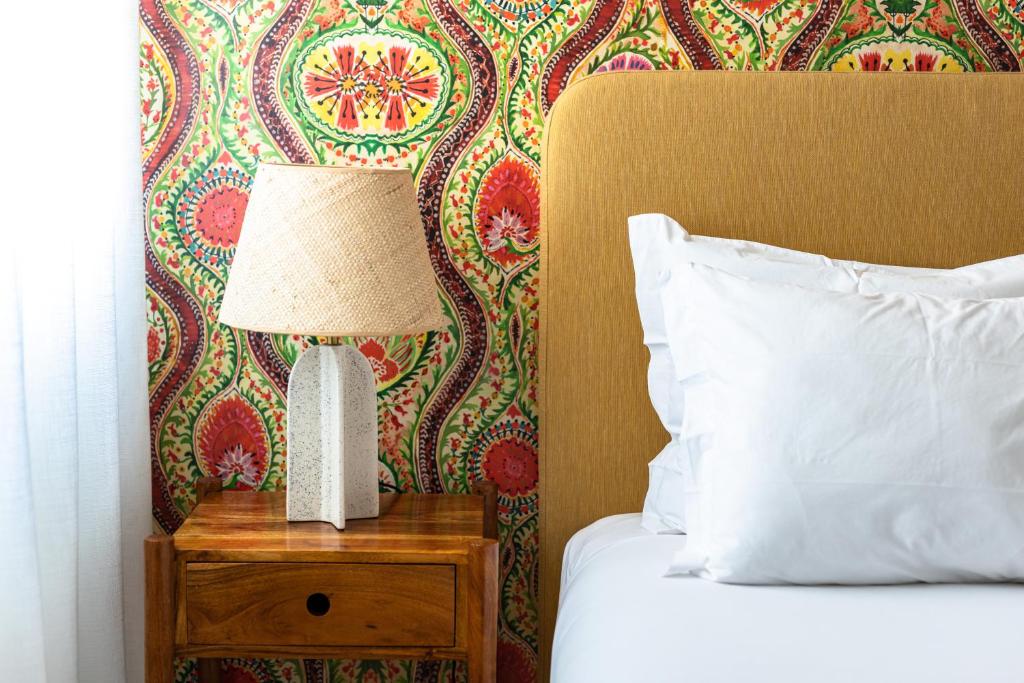 a bed with a lamp on a wooden nightstand next to a bed sidx sidx at Pergola Boutique Hotel in Cascais