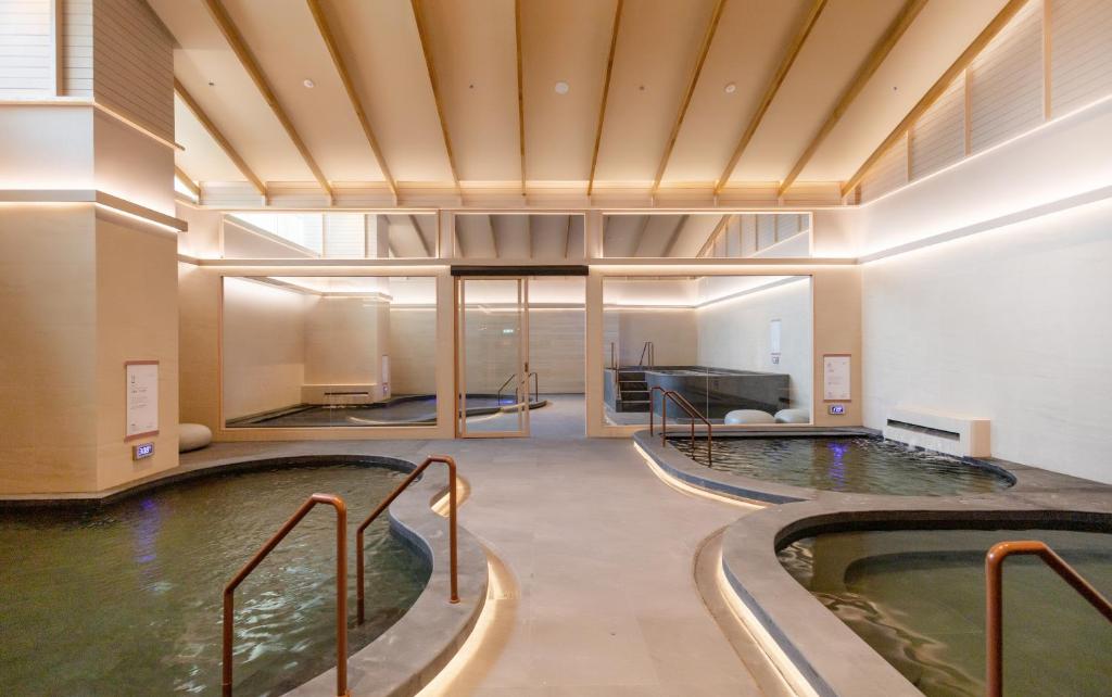 An indoor aquatic area contains several connected pools with handrails and a glass-walled room beyond.
