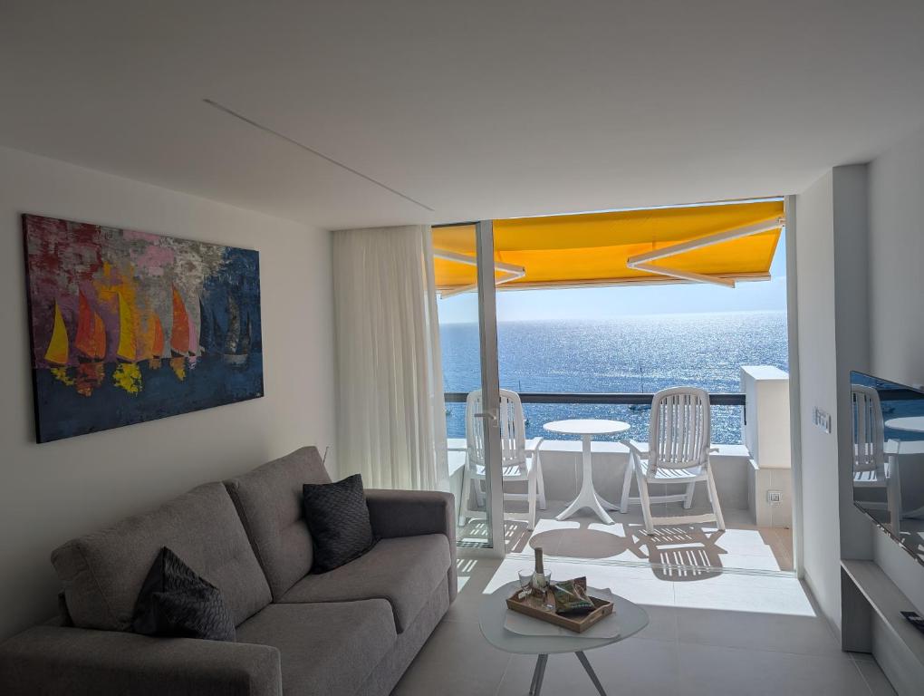 Una sala de estar con un sofá y vista al mar. en Sonido del mar Gran Canaria - Montemarina - luxury panoramic view, en Mogán
