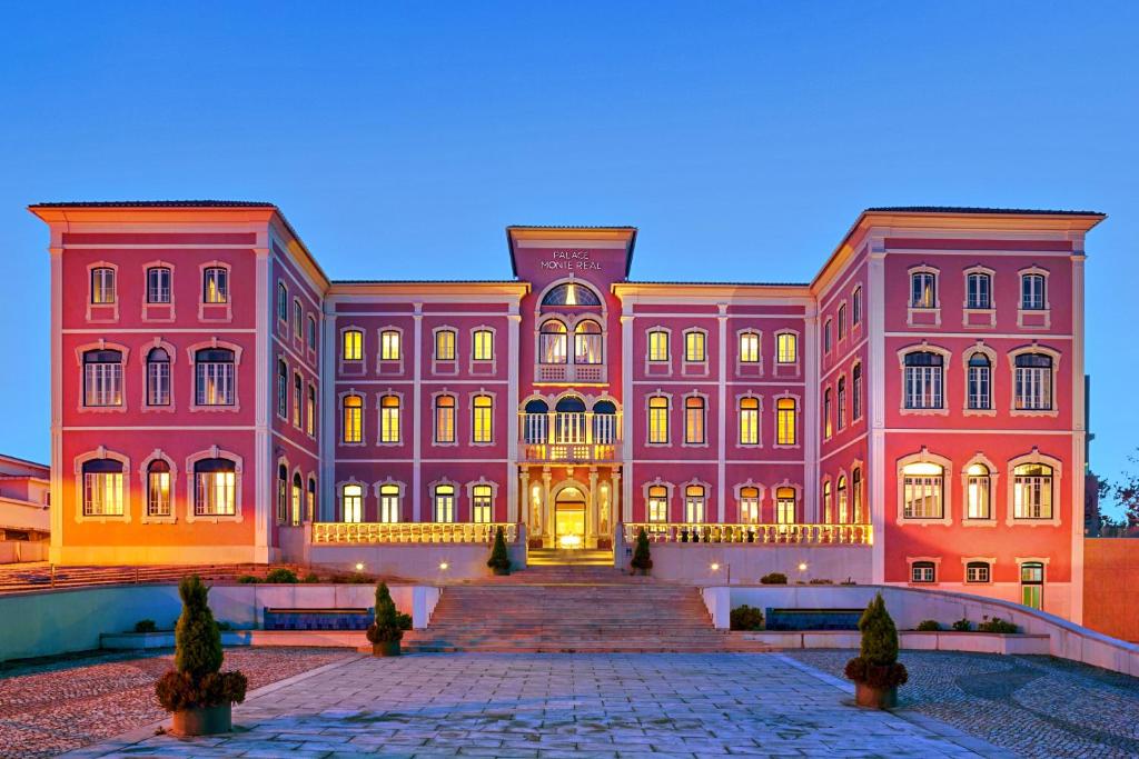 um grande edifício rosa com uma escada em frente em Monte Real - Hotel, Termas & Spa em Monte Real