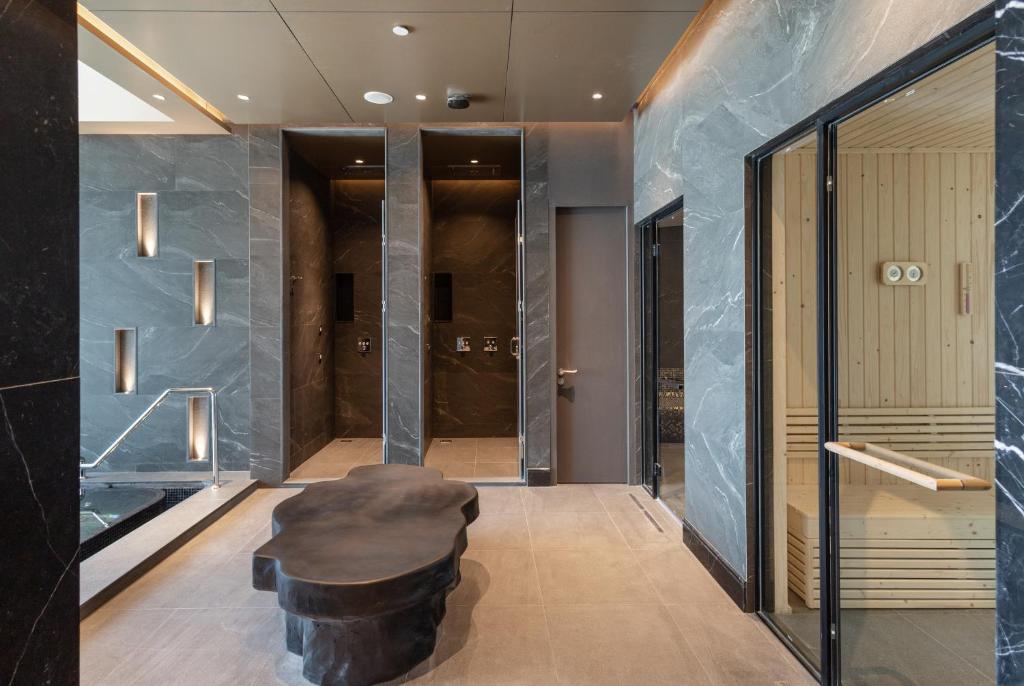 A polished marble spa or wellness lounge with lockers, treatment-room doors and a sauna.