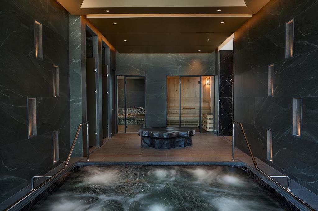 A dark marble hydrotherapy room centered on a bubbling hot tub.