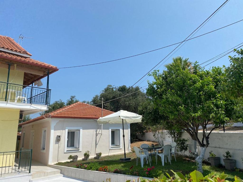 a house with a table and an umbrella in the yard at Nefeli House in Loutsa