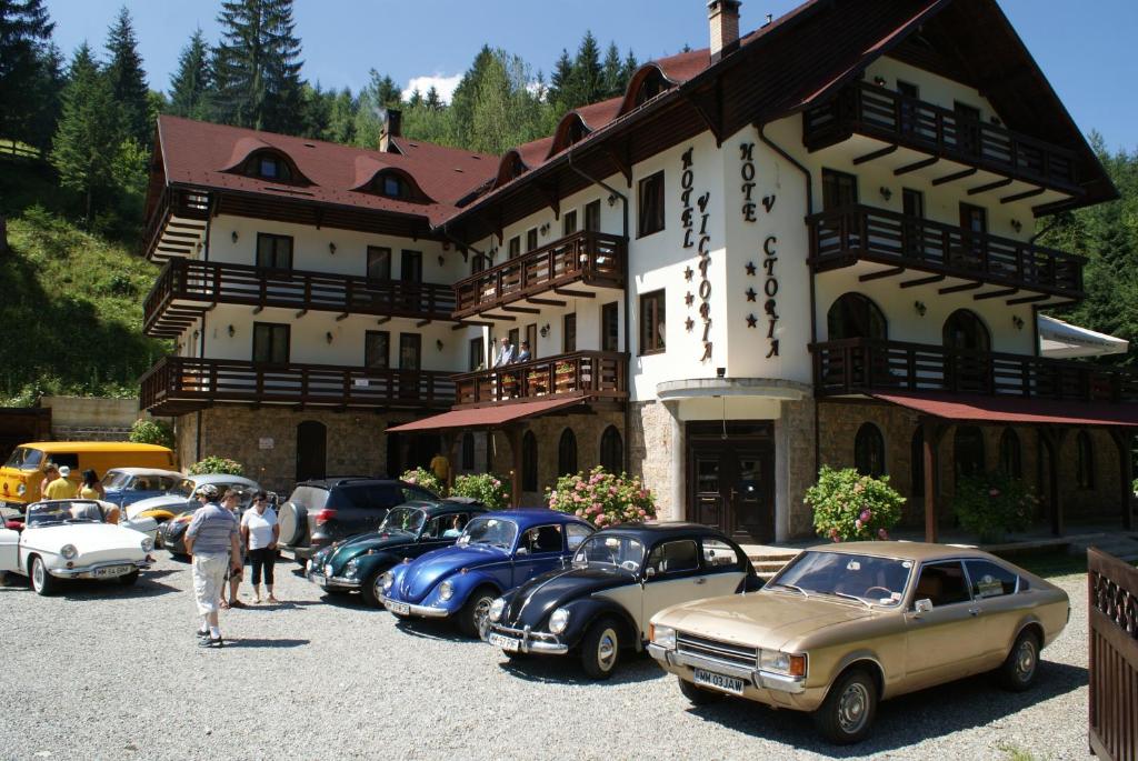 un grupo de coches estacionados frente a un edificio en Hotel Victoria, en Borşa