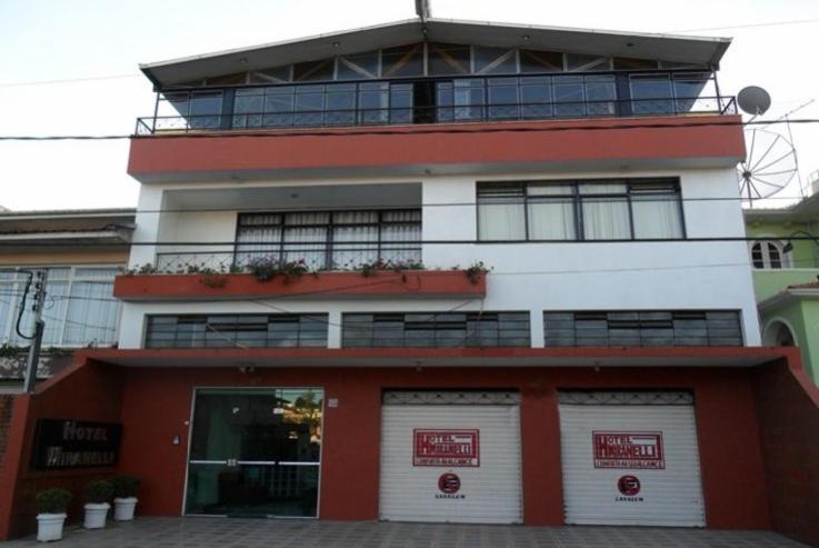 a red and white building with a balcony at Hotel Miranelli in Barbacena