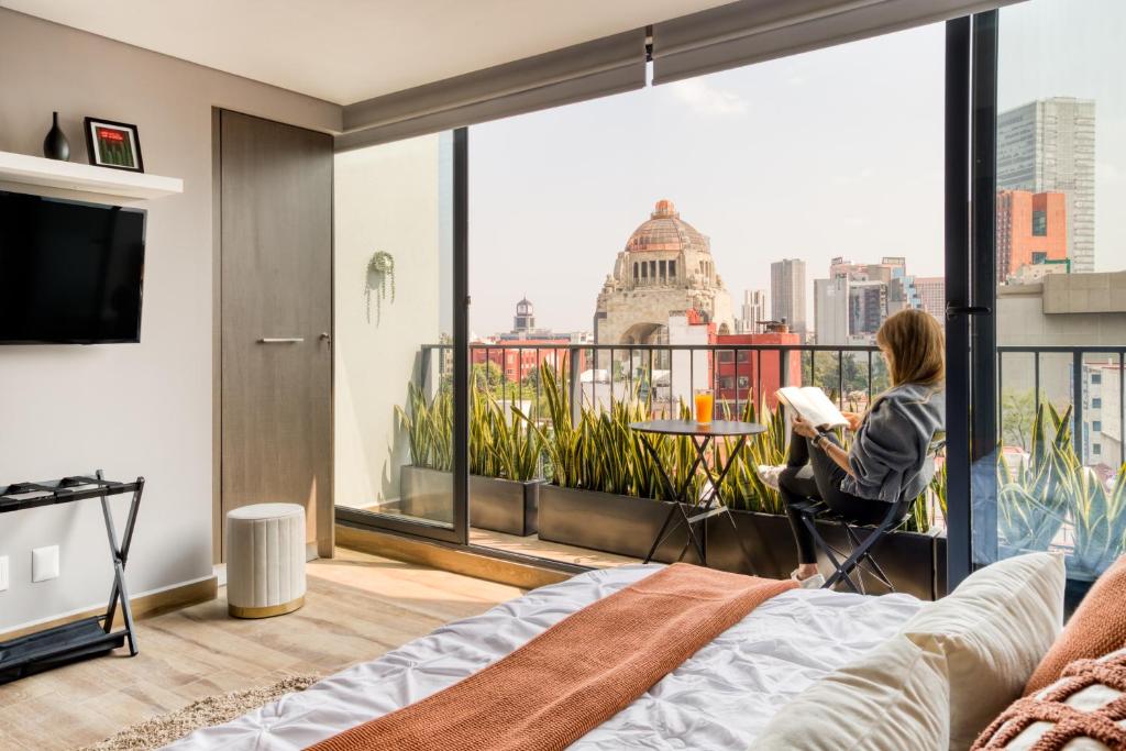 a woman sitting in a chair in a room with a view of the city at Resort Home with Extraordinary City View in Mexico City
