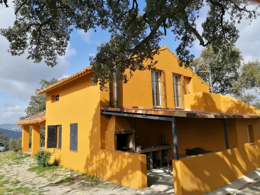 a yellow house with a tree at Finca El Cerro in Ronda
