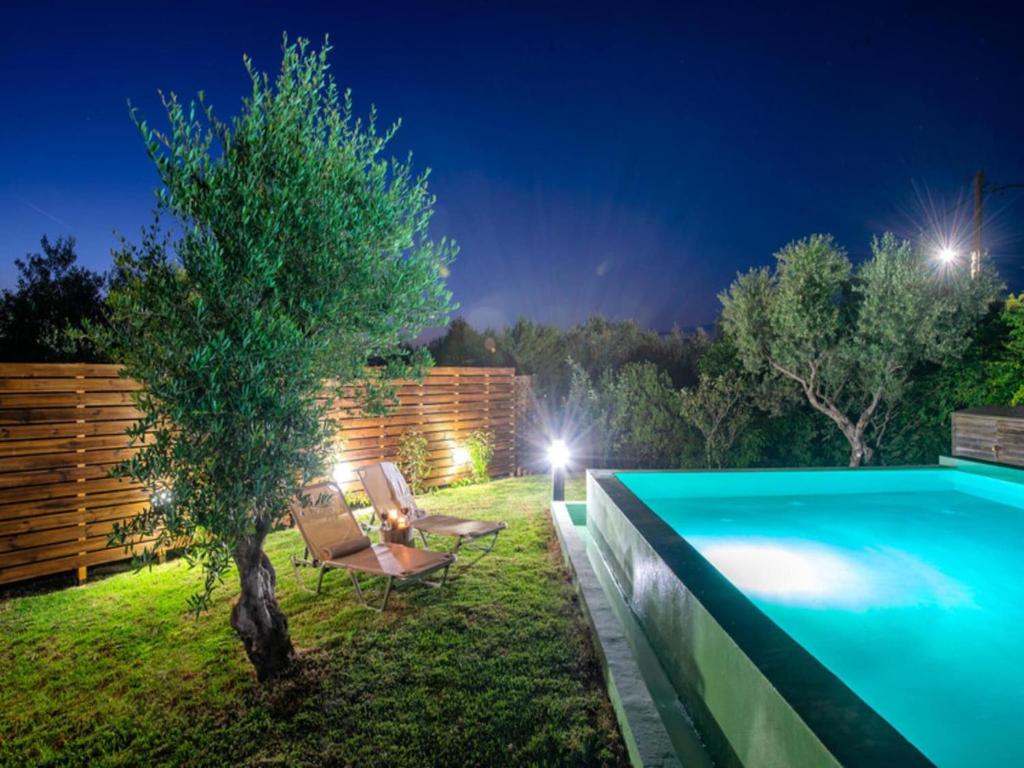 Un patio trasero con piscina y un árbol. en Holiday Residence Rodanthi, Darmarochori, en Darmarochori