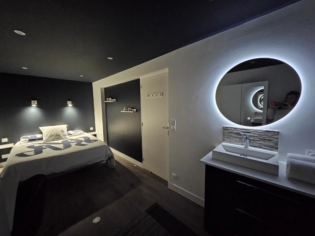 une chambre avec un lit, un lavabo et un miroir dans l'établissement Le Cocon de Marine, à Triel-sur-Seine