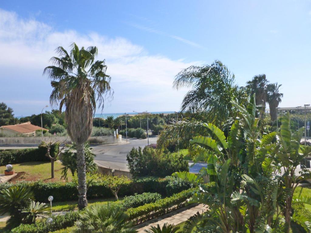 Blick auf einen Garten mit Palmen und einer Straße in der Unterkunft Casa Martina in Marina di Ragusa