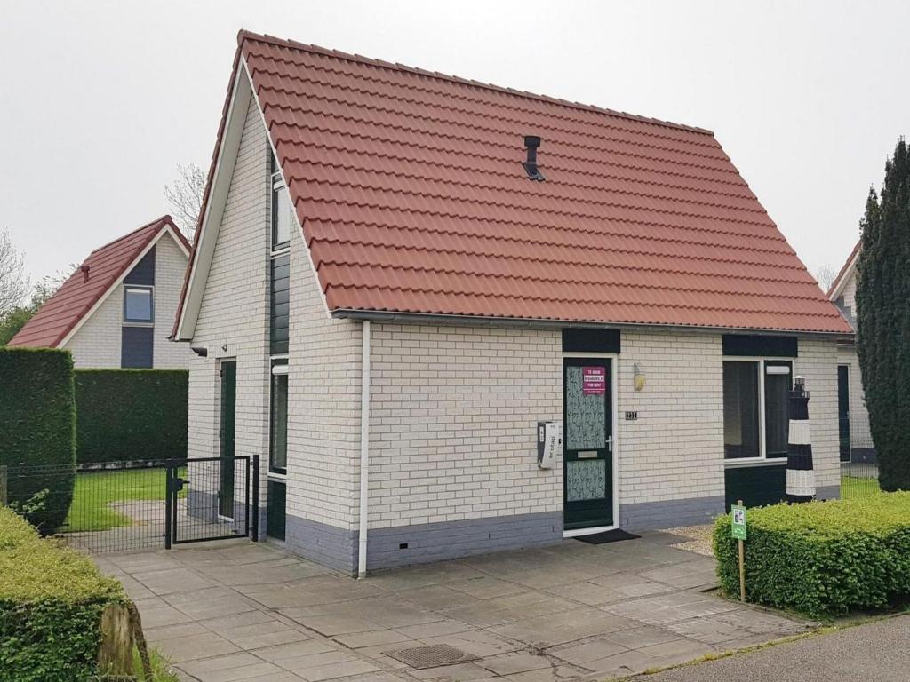 a small white church with a red roof at Holiday Home near Beach in Strandpark in Breskens