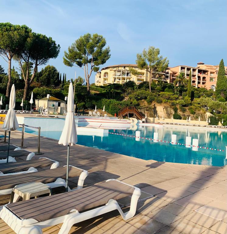 - une piscine avec des chaises et des parasols à côté d'un bâtiment dans l'établissement Superbe T2 club cap Estérel Animations petits et Grands sports&Activités MULTISPORTS, à Saint-Raphaël