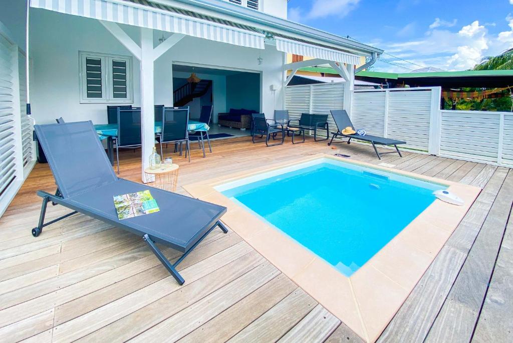 een patio met een zwembad, een stoel en een tafel bij Mqro11 4 et 1 in Le Robert