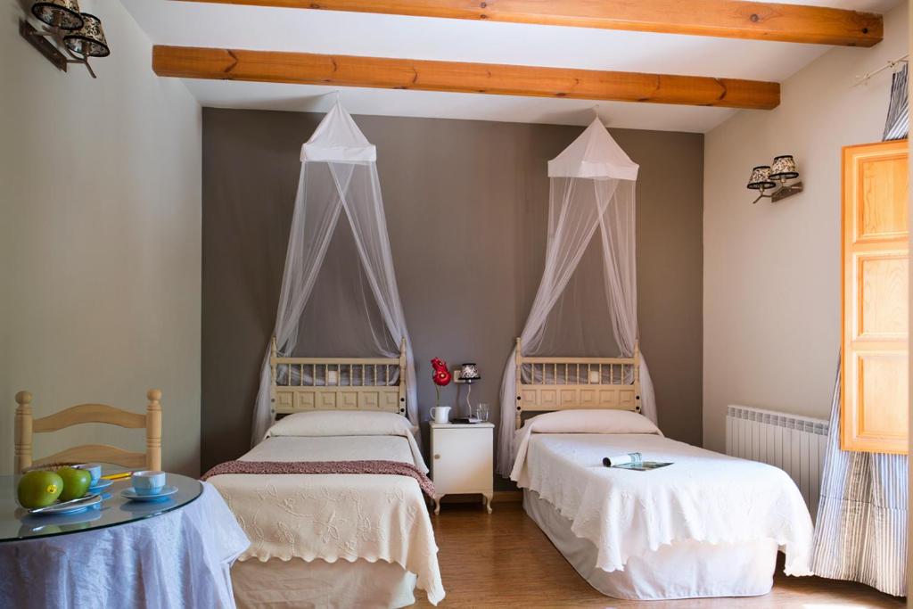 a bedroom with two beds and a table at Casa Rural Miel y Romero in Sevilleja de la Jara