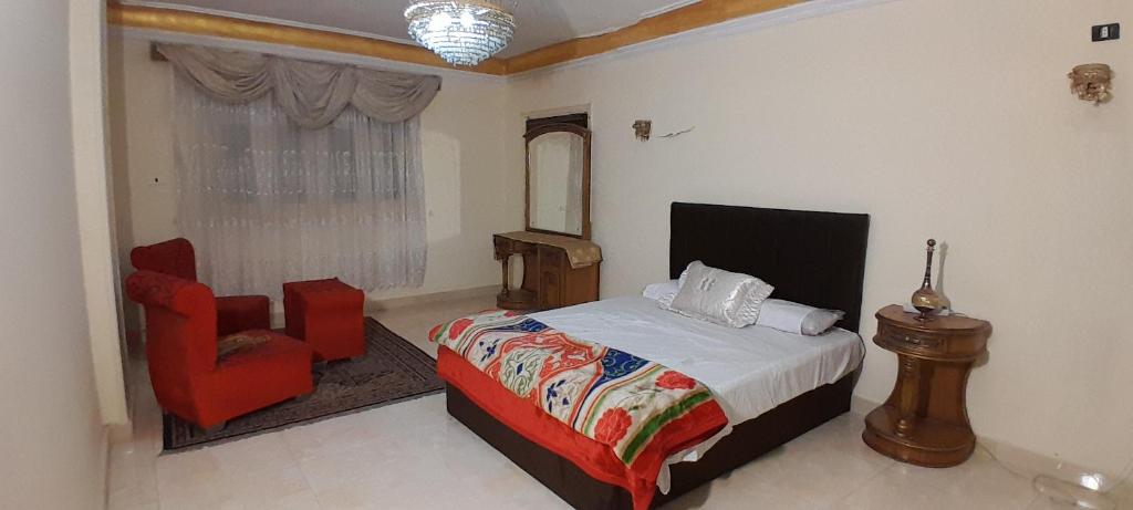 a bedroom with a bed and a red chair at Pyramids Heritage suites in Ghaţāţī