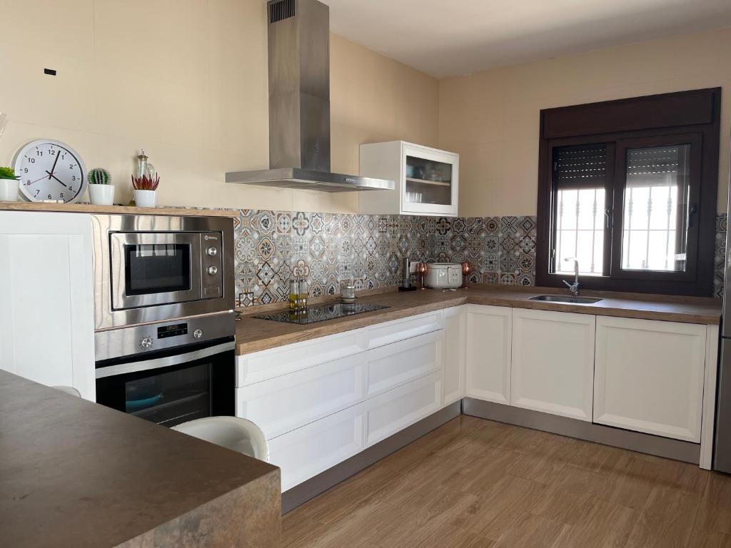 una cucina con armadi bianchi e un orologio sul muro di Rincón del mar a Novo Sancti Petri