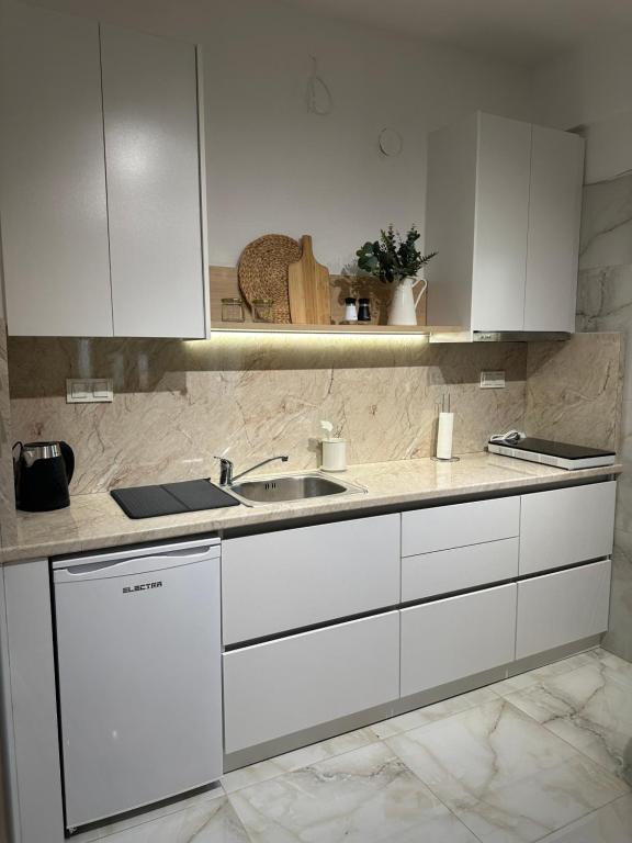 a kitchen with white cabinets and a sink at I&L Apartments in Asprovalta