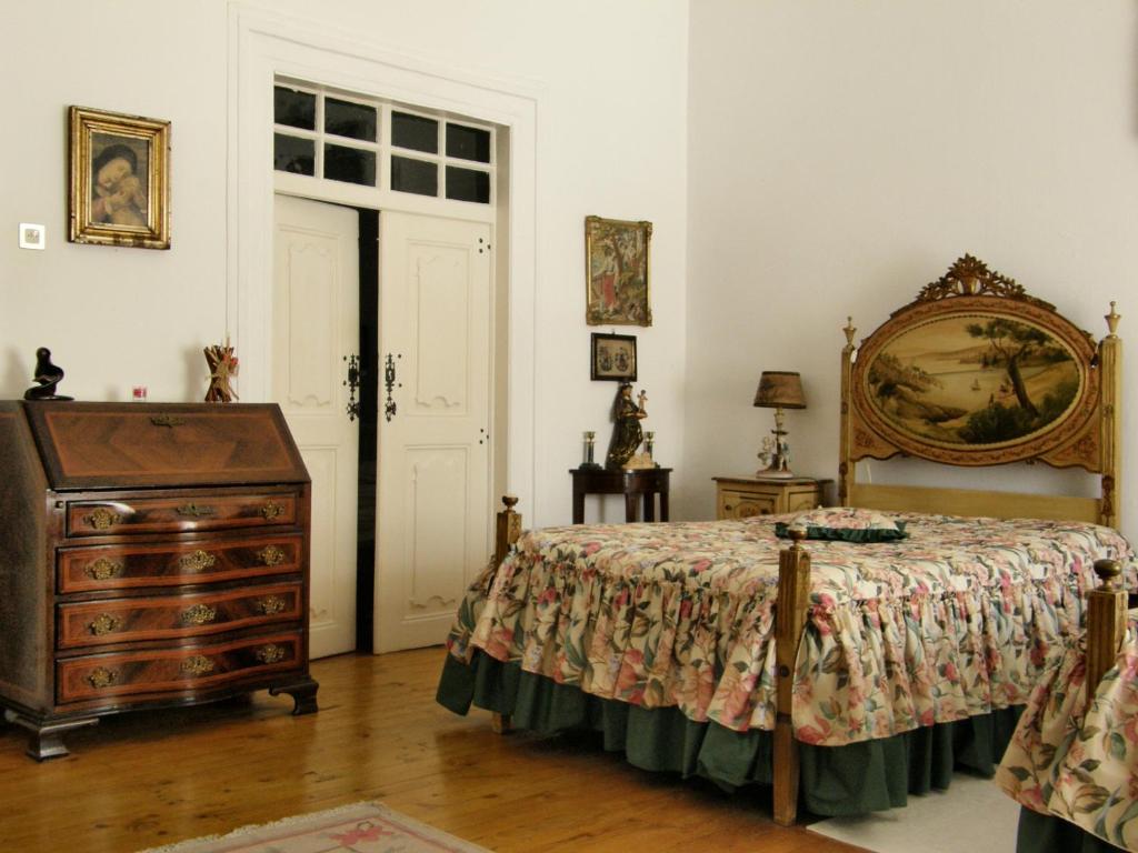 a bedroom with a bed and a dresser and a door at Solar das Avencas in Portalegre