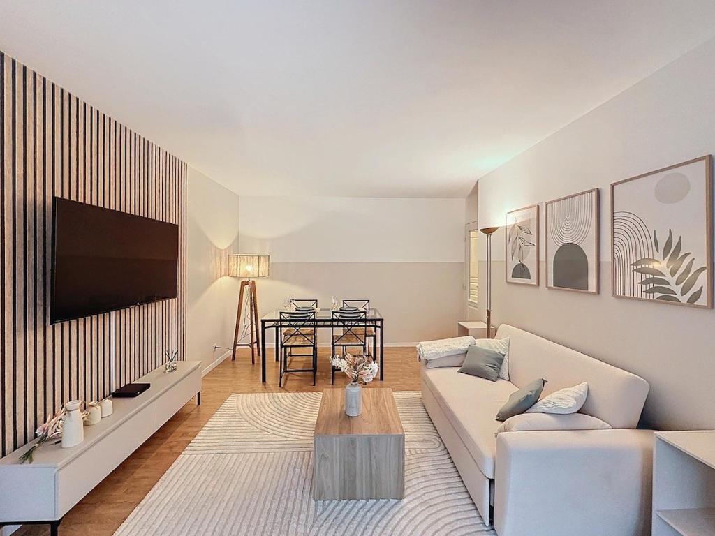 un salon avec un canapé blanc et une télévision dans l'établissement Modern and spacious, apartment near Paris, à Aubervilliers