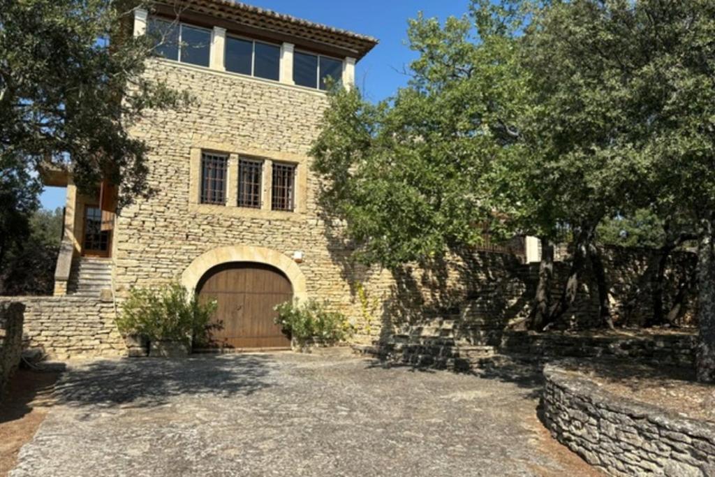 une grande maison en briques avec une porte en bois dans l'établissement Les Campanettes Superb Mas in Provence, à Gordes