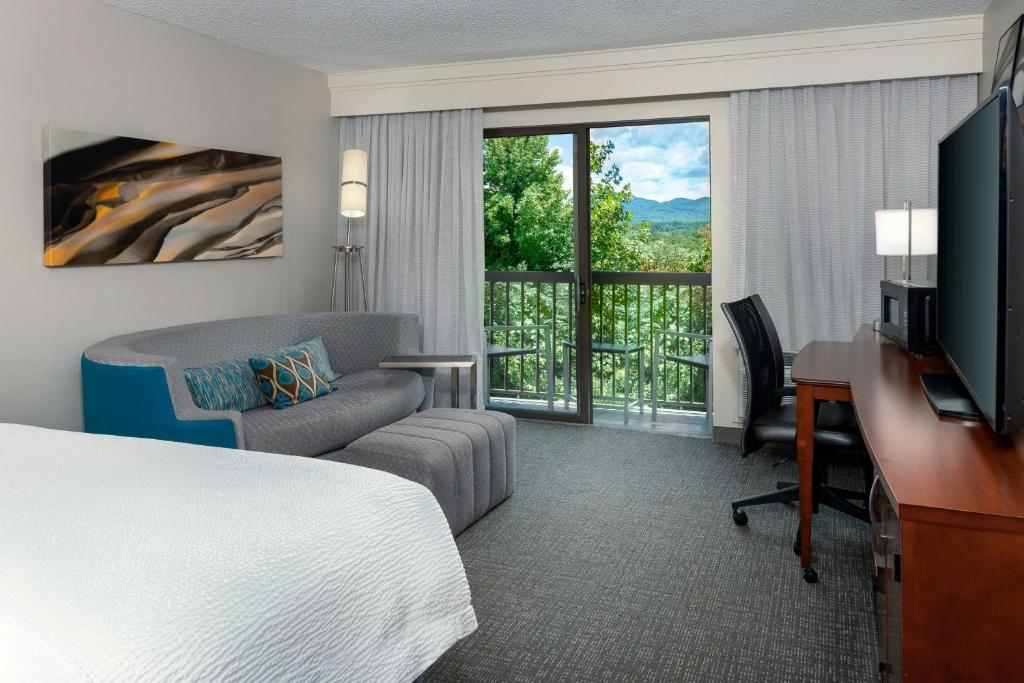 a hotel room with a bed and a desk and a television at Courtyard by Marriott Asheville in Asheville