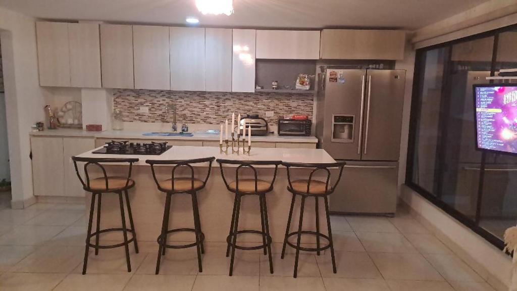 a kitchen with a island with bar stools and a refrigerator at amplio y comodo apartamento in Medellín