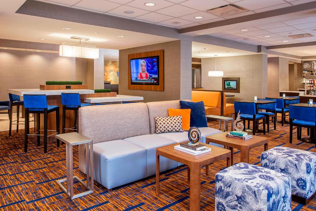 Un vestíbulo con un sofá y mesas y un bar. en Courtyard Binghamton, en Vestal