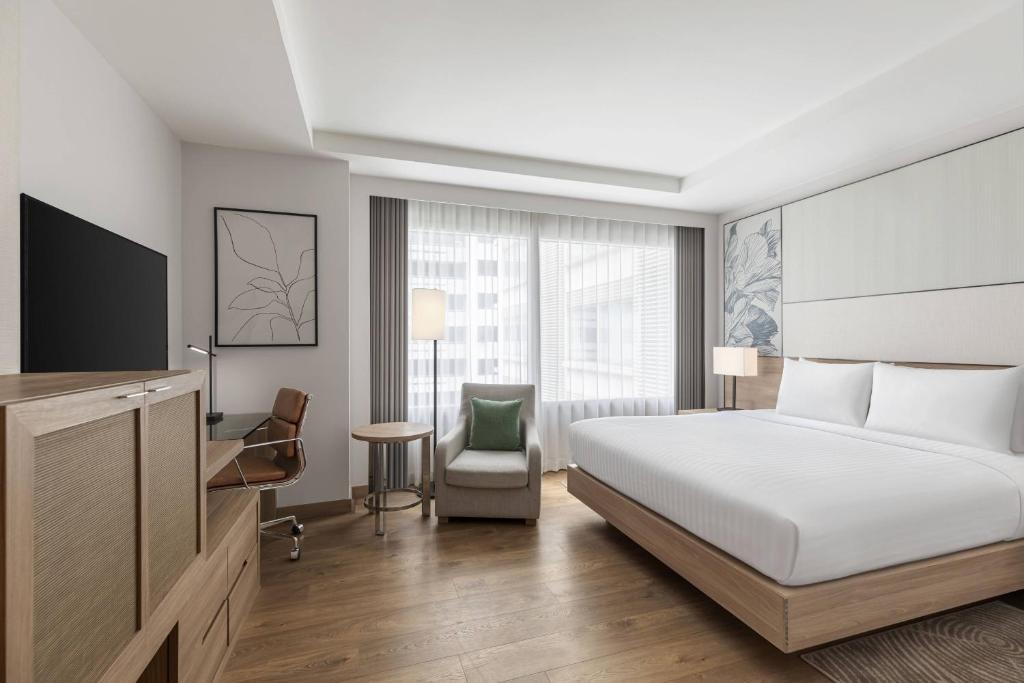 A king-bed room with a lounge chair, work chair and side-positioned television.