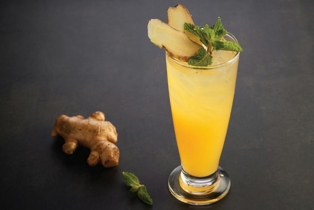 A styled glass of orange juice garnished with ginger and mint.