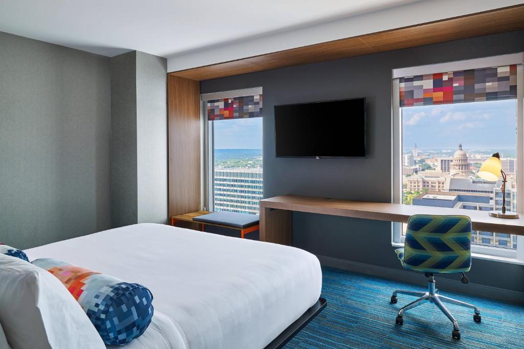 a hotel room with a bed and a desk with a television at Aloft Austin Downtown in Austin