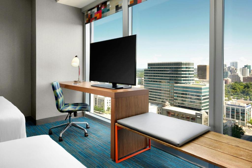 a hotel room with a desk with a television and a window at Aloft Austin Downtown in Austin