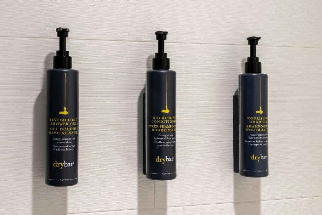 a group of three bottles of hair products on a wall at Aloft Austin Downtown in Austin