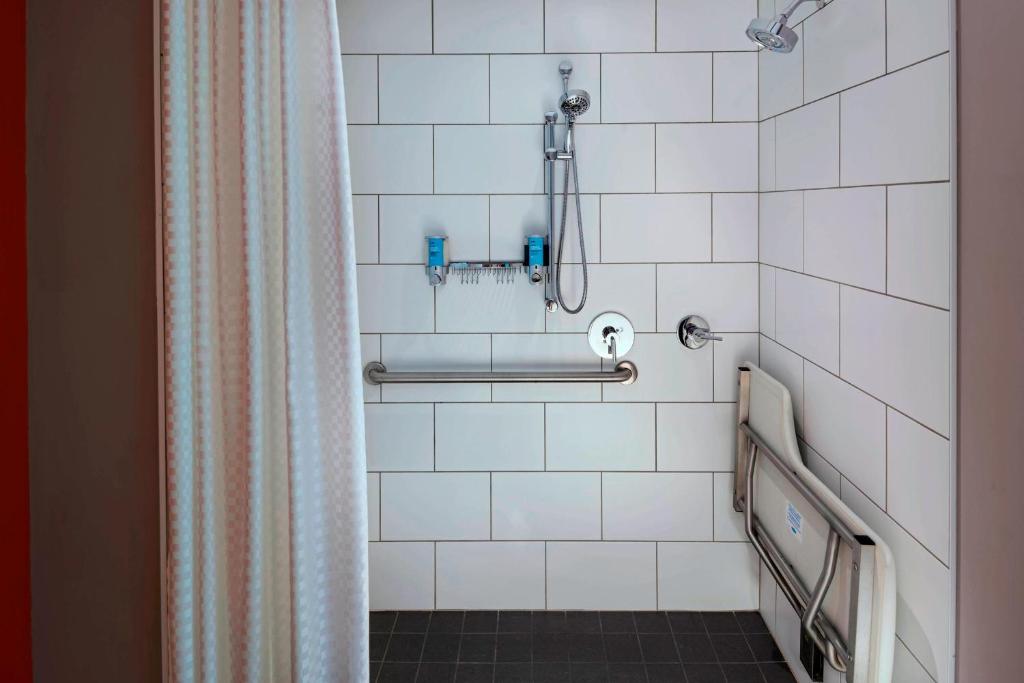 a white tiled bathroom with a shower curtain at Aloft Austin Downtown in Austin