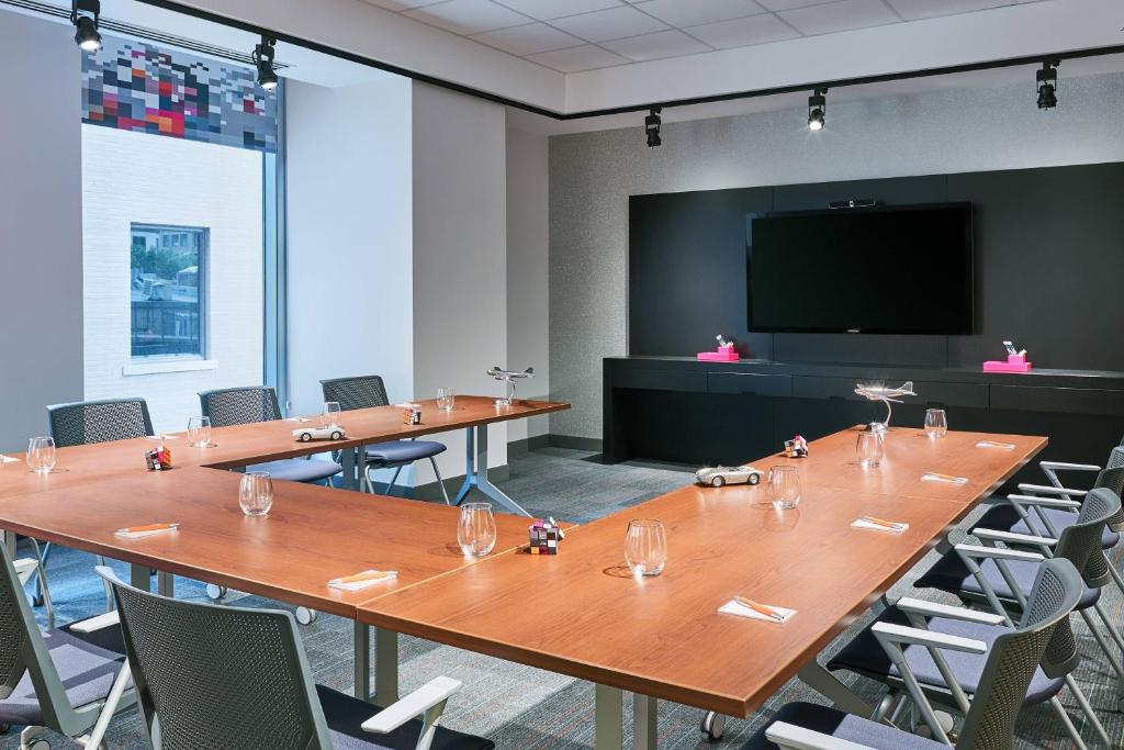 a conference room with tables and chairs and a flat screen tv at Aloft Austin Downtown in Austin