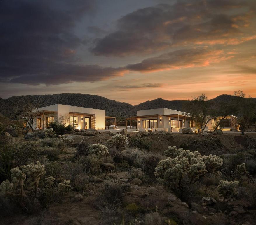 a house in a field with mountains in the background at Fleur in Joshua Tree
