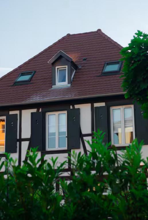 une maison blanche avec un toit marron et des fenêtres dans l'établissement Appartement 2 pièces atypique, à Schiltigheim