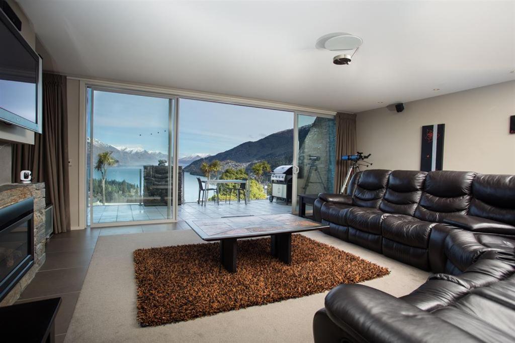 a living room with a leather couch and a table at Downtown Queenstown Apartment in Queenstown