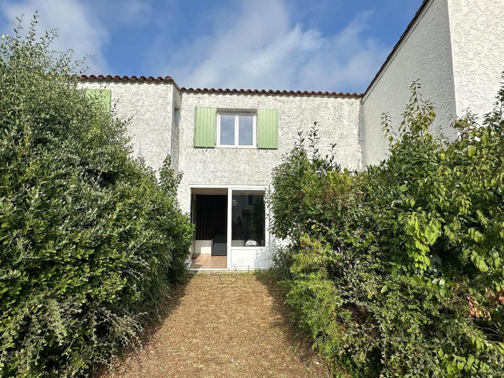 une maison blanche avec une porte verte et des buissons dans l'établissement Villa 4 Pièces, 3 Chambres, Animaux Acceptés, Parking, WiFi, Proche Mer - FR-1-705-92, aux Mathes