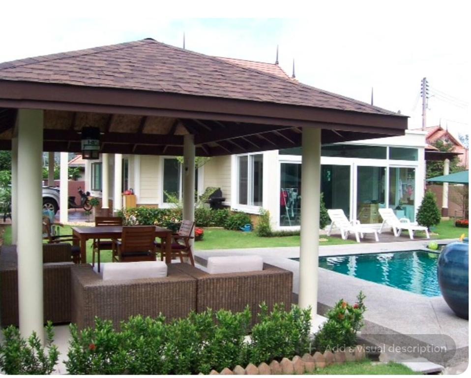 a pavilion with a table and chairs next to a pool at Pool Villa in Thalang in Ban Na Nai