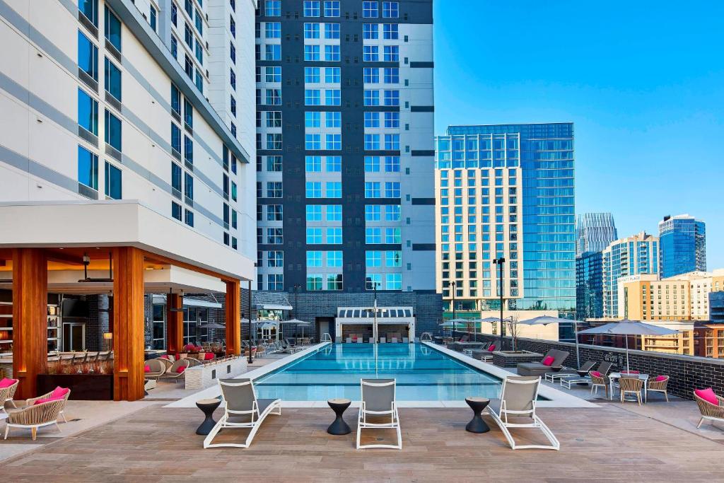 a pool with chairs and tables and buildings at AC Hotel Nashville Downtown in Nashville