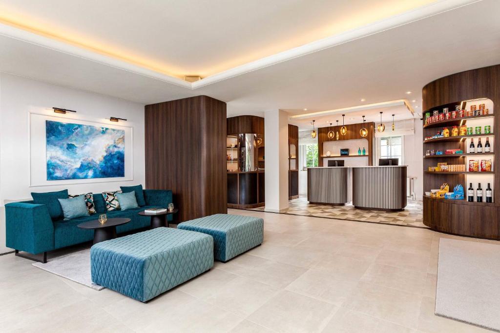 a living room with a blue couch and a table at Courtyard by Marriott Hamburg Airport in Hamburg